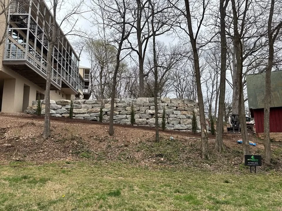 Large natural boulder retaining wall on a wooded hillside