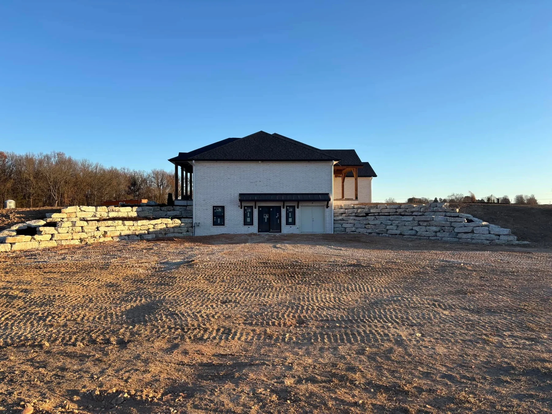Large boulder retaining wall beside a custom home
